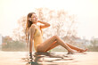 © StockPhotoRepublic - Asian woman in swimsuit relaxing by rooftop pool at sunset. Young tourist woman enjoying golden hour summer vibes by the pool with city skyline backdrop.