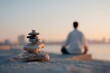 © zorandim75 - Stacked stones calm man practices seated meditation with crossed legs on a concrete platform near water during morning sunrise