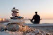 © zorandim75 - Stacked stones balanced calmly with soft sunlight and smooth pebbles as person meditates on sandy beach during serene sunset