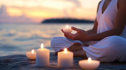 Leinwandbilder - Woman meditates peacefully at sunset by the ocean, holding a lit candle; other candles surround her on rocks, creating a serene atmosphere. : Generative AI