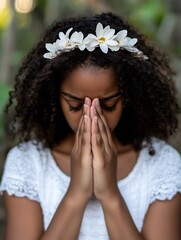 Poster - Young girl with curly hair wearing a white dress and flower crown, prays with hands clasped together, peaceful expression, outdoor setting. : Generative AI