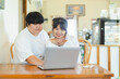 © Sumala - Asian couple enjoying activity together using laptop at home showing happy lifestyle and connection in LGBTQ relationship