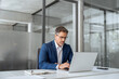 © Stock 4 You - Mature indian ceo business man in suit using pc laptop for trading, looking focused at screen. Middle age latin male entrepreneur businessman working on financial work at desk in office. Copy space