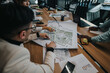 © qunica.com - Business professionals engaged in a collaborative discussion about an urban planning project. They are analyzing maps and brainstorming strategies around a conference table in a modern office.