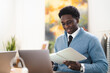 © Studio Marmellata - A young professional man reviews notes in a book at his desk. He is wearing a blue sweater and tie, working from his home office.