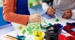 © CineLens25/peopleimages.com - Education, hands and children with painting for kindergarten, creativity or skills development. Closeup, drawing and kids as students for artwork project, learning or motor growth with brush in class