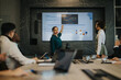© qunica.com - Diverse business people engaged in a meeting as a presenter discusses growth charts. The group collaborates to analyze performance data projected on a screen, fostering teamwork and strategic planning