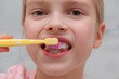 © 7707601 - Young blonde girl brushing her teeth with a toothbrush, closeup. Morning and evening routine.