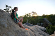 © bilanol - Woman hiker seated alone on rocky mountain cliff enjoying view of evening nature on wilderness trail. Active way of life concept