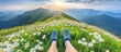 © photopixelstudio - Person's feet on a mountaintop meadow, overlooking a vast vista of rolling hills and mountains at sunrise or sunset