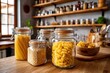 © olgasun - An indoor shot of assorted dry pasta in jars, resting on a wooden countertop in a kitchen, showcasing various types and sizes and providing visual appeal.