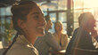 © mian - A smiling woman with a braid in a bright room with other people in the background enjoying sunlight