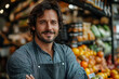 © sofiko14 - Smiling man in apron inside fresh food market surrounded by produce