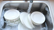 © Jessica - Dishwashing. Warm soapy water fills the sink with clean plates ready for drying.