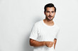© SHOTPRIME STUDIO - Smiling young man wearing a white t-shirt stands confidently, looking directly at the camera with a friendly expression on his face against a plain background.