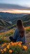 © Yana - Woman sits in poppy field overlooking mountains at sunset enjoying vista