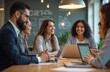 © miss irine - Group of diverse businesspeople working together in modern office setting. Team members collaborate, discussing ideas. Smiling, happy people use laptops at meeting table. Teamwork, communication,