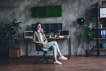 young female programmer in casual attire sitting at a stylish home office with multiple screens disp