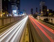 © fara - Night city highway traffic light trails. Urban cityscape at night with speeding cars creating vibrant light streaks.