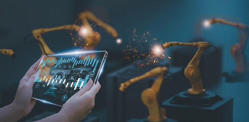 Wall Mural - industry engineer in smart factory using transparent glass tablet to control automated robotic arm w