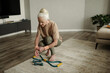 © Mediaphotos - Senior woman kneeling, using dumbbells and resistance bands for exercise in spacious modern living room with wooden floors and neutral decor