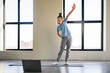 © Sergey - A little girlis actively participating in an online workout session, stretching and focusing on her form in a spacious gym filled with natural light.