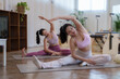 © Phimwilai - Two young women sitting on yoga mats in a pilates studio, stretching their bodies and enhancing flexibility while focusing on well being and mindful relaxation during their workout