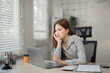 © MINAE - Young Asian businesswoman is working on a laptop and feeling stressed from work in the office, she is having problems and is looking for solutions