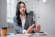 © MINAE - Young Asian businesswoman refusing a snack and showing stop gesture with her hands while sitting at her office desk, promoting healthy eating habits at work