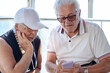 © luciano - Elderly pensioner couple joyfully sharing a digital moment looking at smartphone together. Modernity, friendship, positivity and companionship concept, staying connected in the digital age