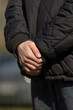 © Viktar - A person dressed in a stylish black jacket is standing still while holding their hands together in a thoughtful manner
