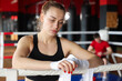 © New Africa - Woman wrapping her hands on boxing ring