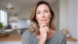 © Jinyang - A contemplative middle-aged woman with light brown hair wearing a green sweater stands in a modern kitchen with her hand on her chin deep in thought