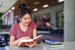 © snowing12 - Young Asian Woman Reading Book at Library Table Learning Studying for Exam Education with Focus on Knowledge Success and Bright Future