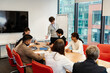 © Drobot Dean - A young White man with glasses is leading a team meeting with a multinational group of colleagues during an internship, discussing ideas and presenting documents in a modern conference room.