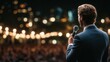 © Ant - A man in a suit speaks into a microphone on stage to a blurred audience under warm, glowing lights at night.