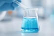 © Сергей Захаров - high-angle view of scientist in laboratory swirling beaker with blue chemical liquid wearing safety gloves and goggles