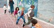© peopleimages.com - Hopscotch, kids and playing with outdoor game at Kindergarten for childhood development. Group, children or learners jumping with teacher for fun activity, hopping or skipping on school playground