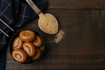 Wall Mural - tasty sweet caramel candies and sugar on wooden table, top view. space for text