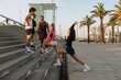 © Drobot Dean - Two female athletes stand and stretch while a group of three male athletes stand opposite them, on the stairs