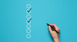 © vision code - Hand marking a checklist with a pen on a blue background showing progress and task completion status real estate business ,technology ,selling ,purchasing ,agreement