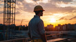 © Gautier Normand - Un ouvrier observe le coucher du soleil depuis un chantier de construction. Les silhouettes des bâtiments et des grues se dessinent à l'horizon, créant une ambiance tranquille.
