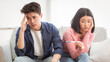 © Prostock-studio - Unwanted Pregnancy. Upset Child-Free Chinese Couple Holding Positive Pregnancy Test Sitting On Sofa Indoors. Unplanned Childbirth, Unintented Pregnancies And Unhappy Parents-To-Be Concept