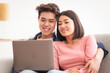 © Prostock-studio - Lovely Japanese Couple Using Laptop Sitting On Sofa With Computer And Watching Movie Online Relaxing In Cozy Living Room, Spending Time Together On Weekend At Home.