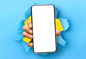 Mobile App Promo, Great Offer. Closeup of hand holding smartphone with white empty screen showing device close to camera breaking through blue paper sheet. Blank display with free copy space, mock up