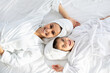 © Prostock-studio - Happy young mother and little daughter in bathrobes and towels on heads laying on bed face to face and smiling at camera, top view. Cheerful mom and kid having beauty day at home