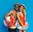 © Prostock-studio - Summer Fun. Cheerful black couple in swimwear enjoying summertime with inflatable toys, posing over blue studio background, copy space
