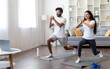 © Prostock-studio - Training At Home. Sporty indian couple doing glutes exercise in front of laptop, happy young eastern spouses watching online tutorials and exercising in living room, practicing sports together