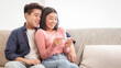© Prostock-studio - Joyful Asian Couple Holding Positive Pregnancy Test Embracing Sitting On Sofa At Home. Happy Parents-To-Be, Childbirth, Young Chinese Family Awaiting Baby Concept. Selective Focus