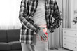 © New Africa - Arthritis. Man suffering from hip joint pain at home, closeup. Black and white toning with red color accent